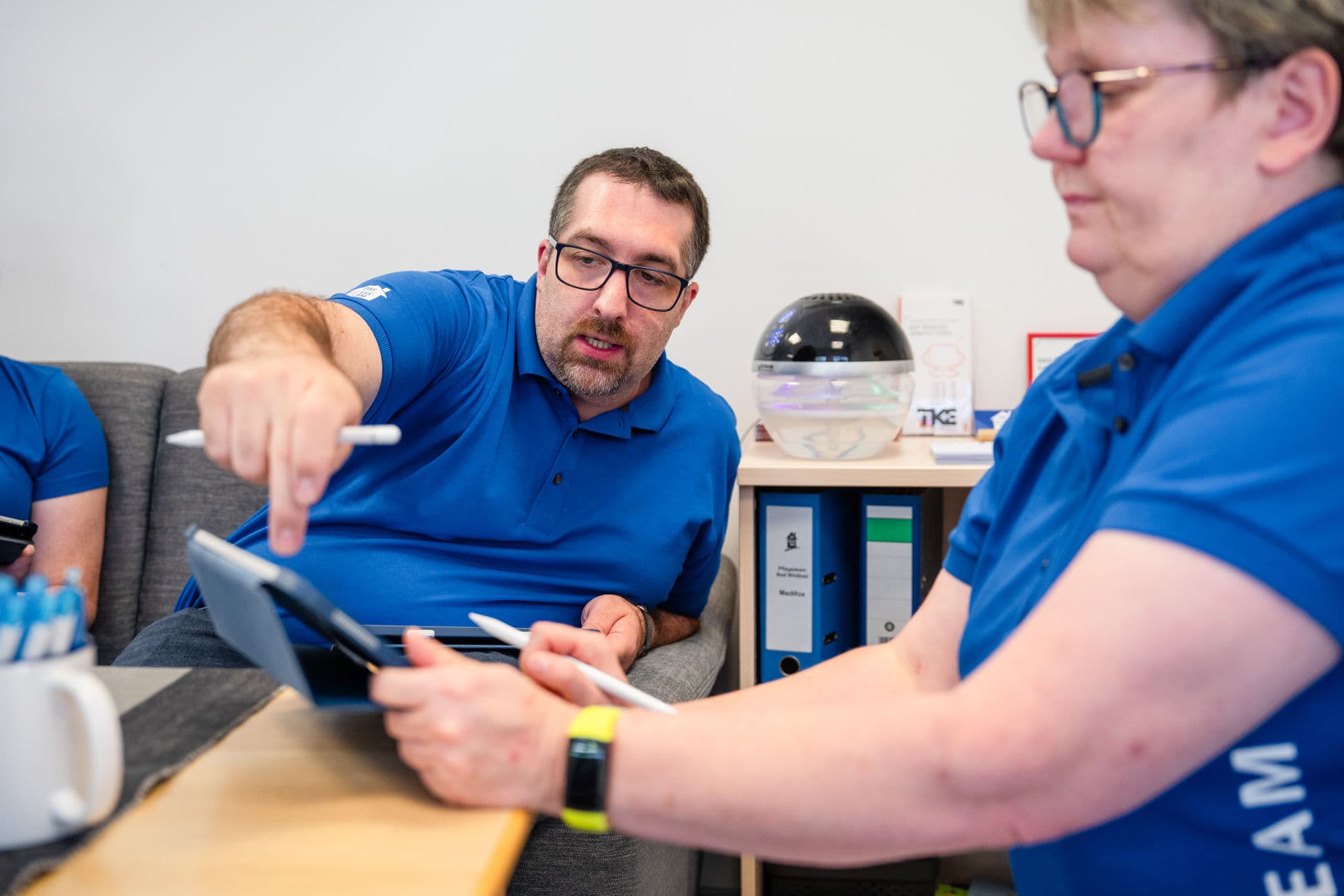 Mitarbeiter des Pflegeteams besprechen gemeinsam die Pflegeplanung anhand eines Tablets